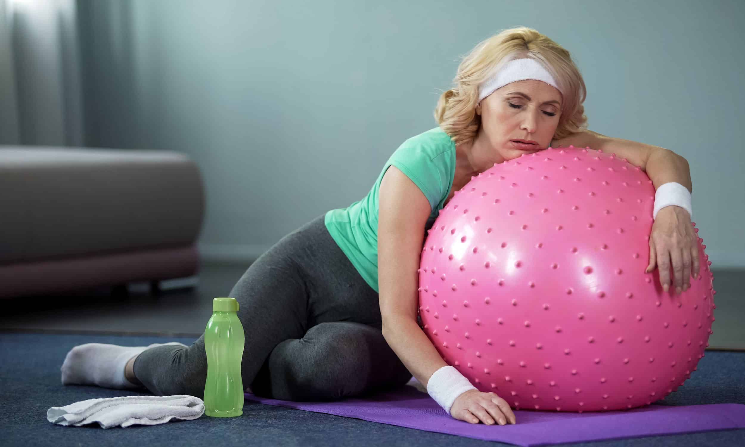 woman resting on exercise ball after a tiring workout