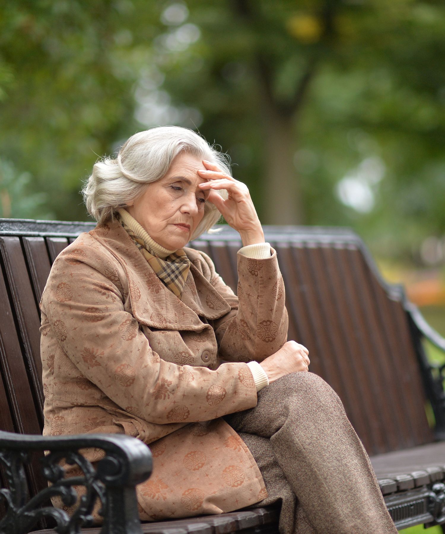 older woman sitting on a park bench in pain due to Dilated Cardiomyopathy