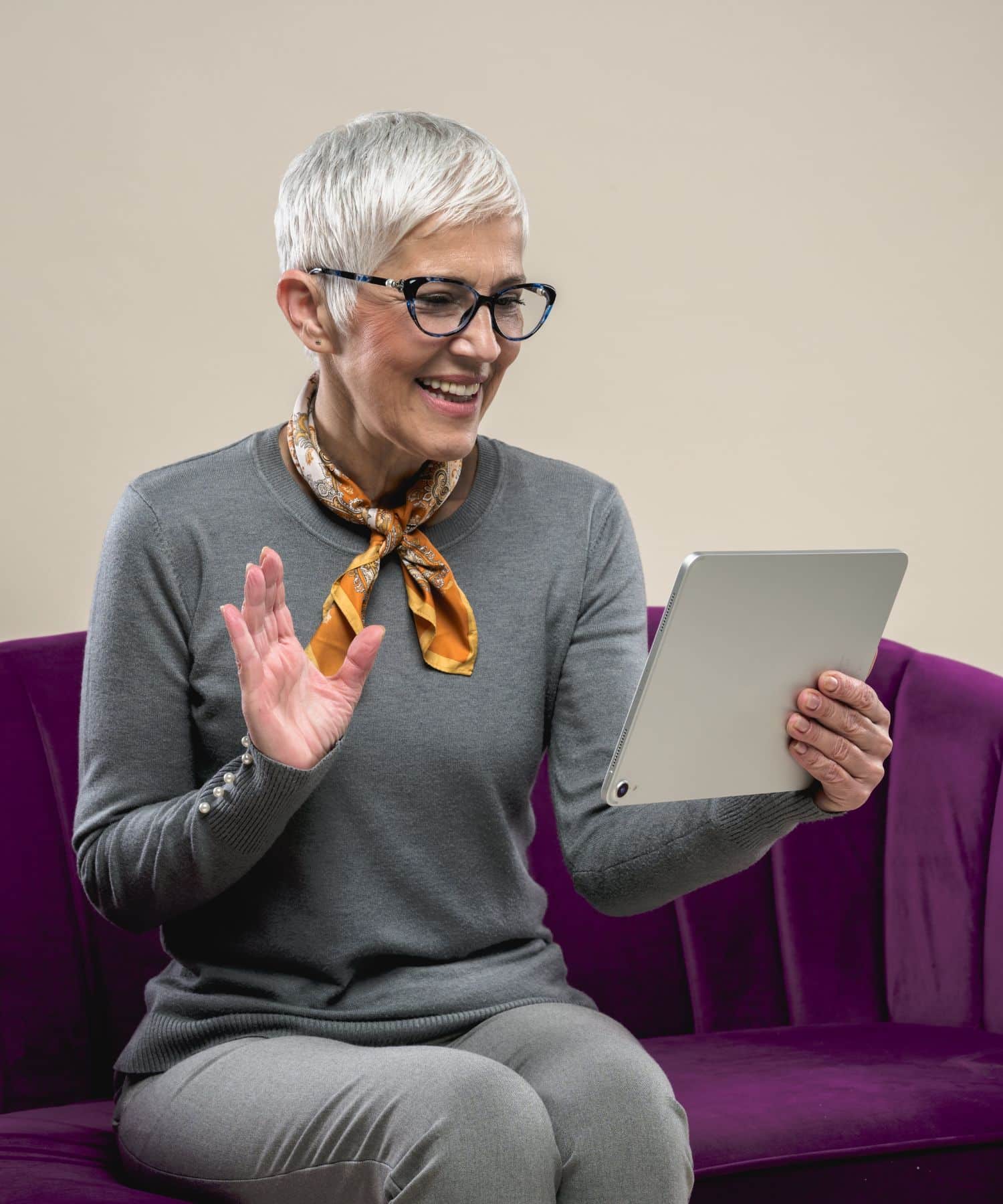 woman sitting on a purple couch talking to someone on a tablet